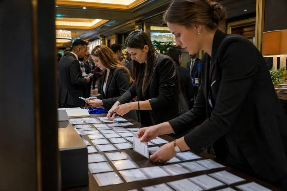 Trzy hostessy przy stanowisku rejestracji gości na konferencji firmowej w hotelu